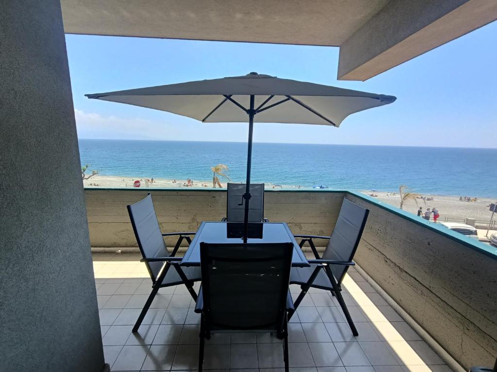 een tafel met een parasol op een balkon met uitzicht op het strand bij CASA SOFIA Via Amerigo Vespucci n18 in Roccalumera