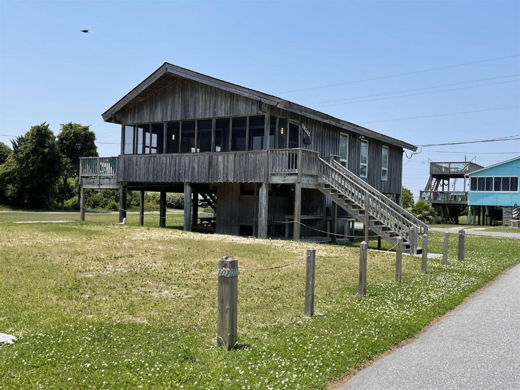 Un gran edificio de madera con un porche y una valla. en Gray Eagle House 58202, en Hatteras
