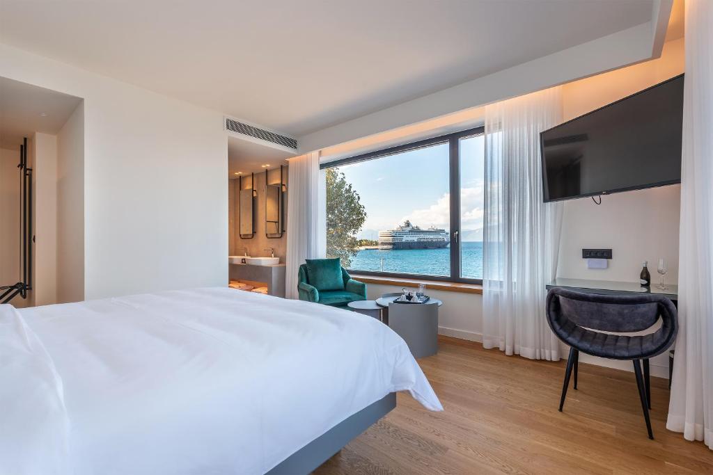 a bedroom with a large bed and a large window at Amario Suites Hotel in Aigio