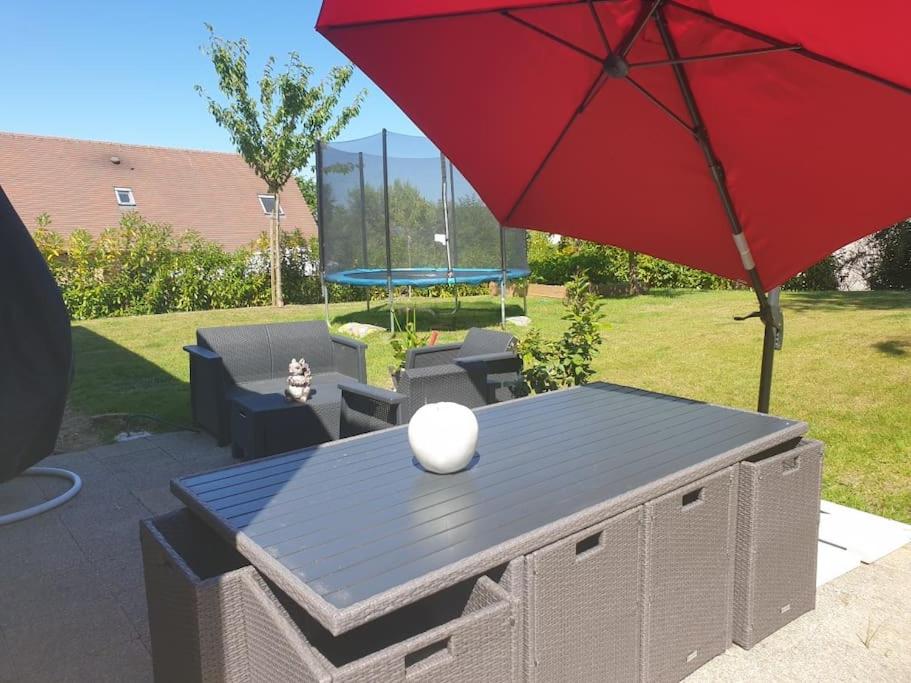 Un patio con una mesa y una sombrilla roja. en Cosy maison Honfleur 2 chambres parking jardin et jacuzzi, en La Rivière Saint Sauveur