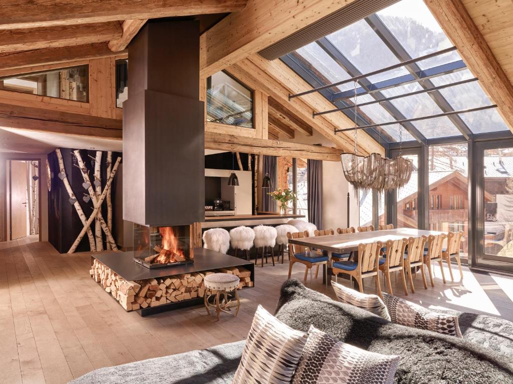 un soggiorno con camino e tavolo con sedie di Firefly Luxury Suites a Zermatt