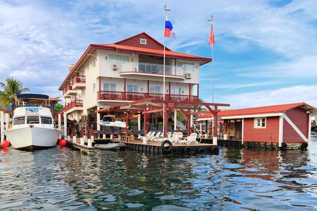 un grand bâtiment sur l'eau à côté d'un bateau dans l'établissement Divers Paradise Boutique Hotel, à Bocas del Toro