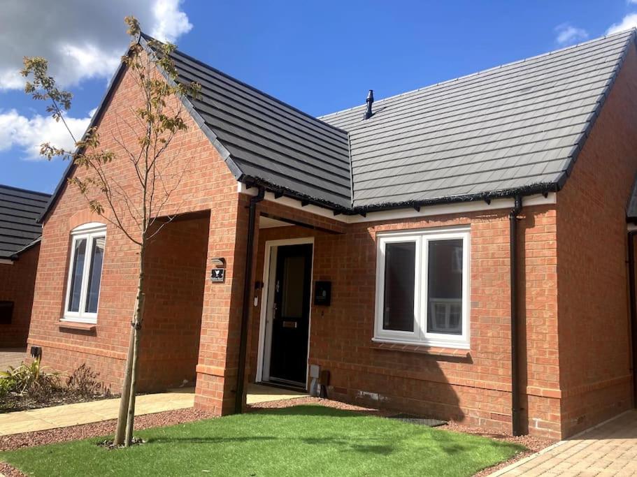 a red brick house with a black roof at Robins Nest Luxury Bungalow in Northampton