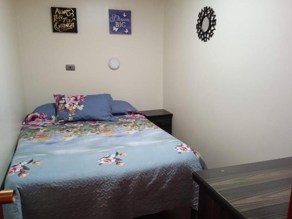Un dormitorio con una cama con flores. en Residencial la Cabaña, en Santiago