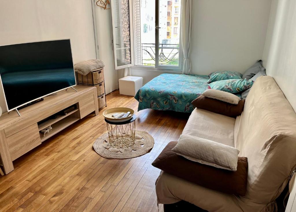 ein Wohnzimmer mit einem Sofa und einem Flachbild-TV in der Unterkunft Havre de Paix 10 mn Centre Paris in Clichy