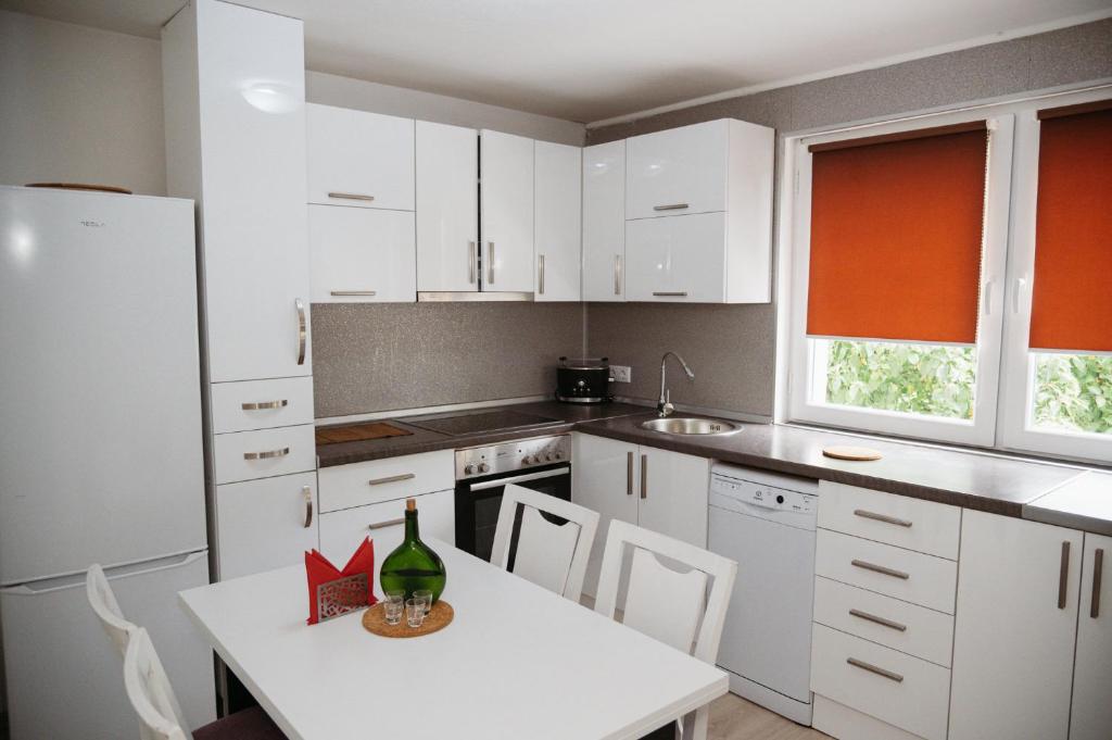 a kitchen with white cabinets and a table with a wine bottle on it at Apartmani Romić R in Novi Travnik