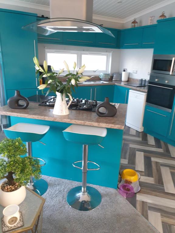 eine Küche mit blauen Schränken und einer Theke mit Stühlen in der Unterkunft 2 bed lodge sleeps 6 in Rhyl