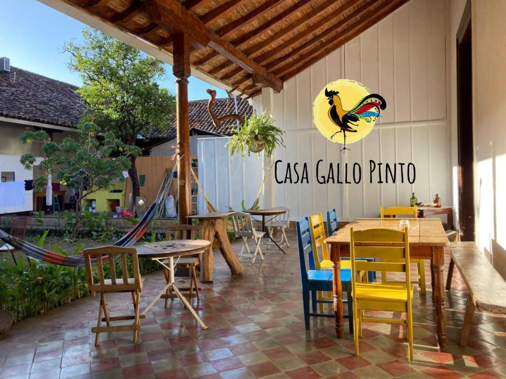 een patio met tafels en stoelen en een vogel aan de muur bij Casa Gallo Pinto in Granada