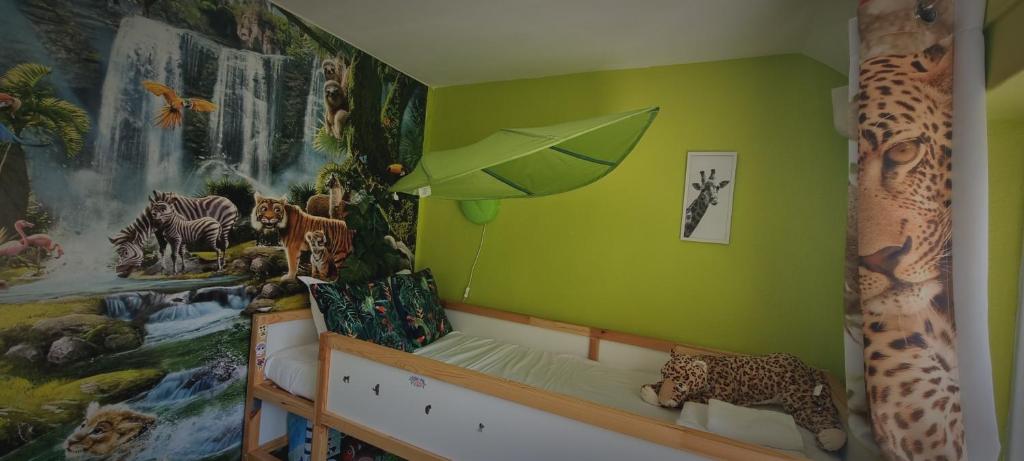 a childs bedroom with a green wall with animals on it at Lovely 5-bed home with free parking and garden in Addington