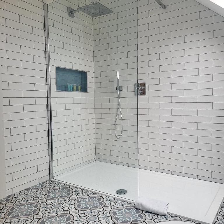 a shower with a glass door and a tile floor at An Creagán Rooms in Inisheer