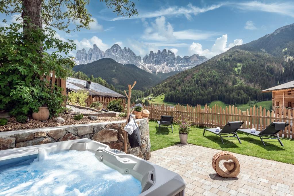 una bañera de hidromasaje en un patio con montañas al fondo en Oberkantiolhof en Villnoss