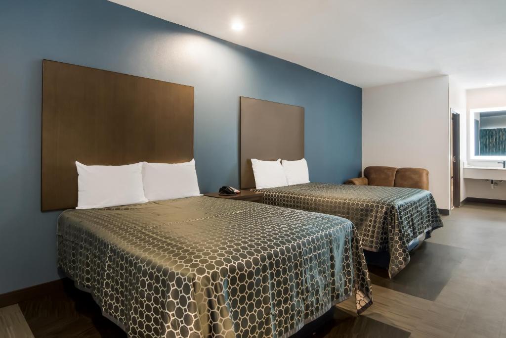 two beds in a room with blue walls at Scottish Inns- Forest Hill in Forest Hill