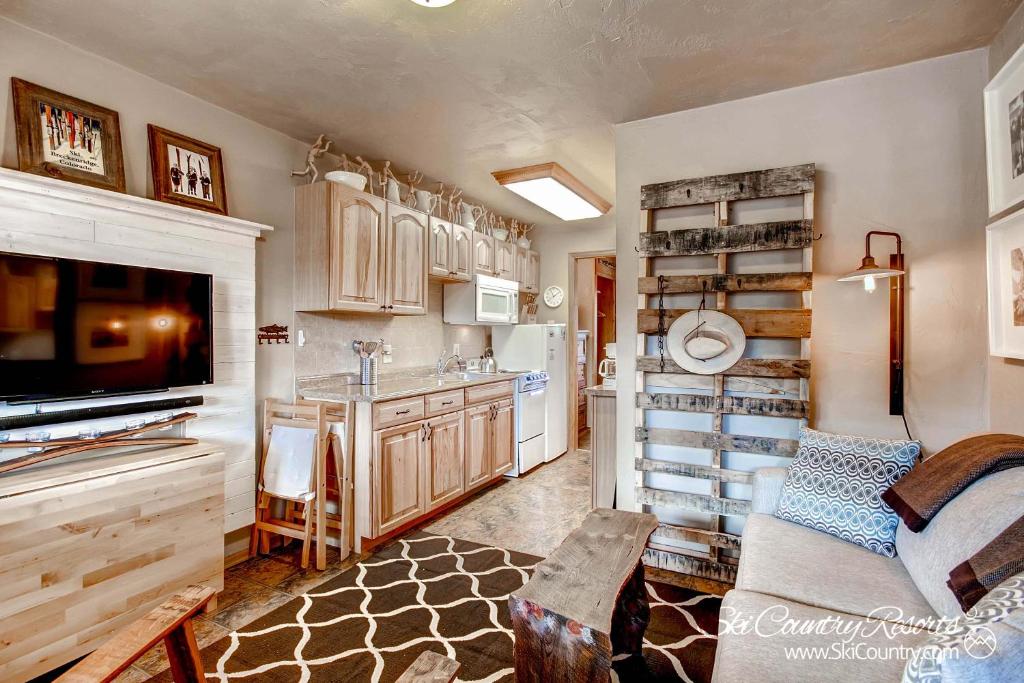 a living room with a kitchen with a sink and a refrigerator at Outstanding Top Floor Condo, Stunning Updates with Meticulous Touches Throughout PM7C in Breckenridge