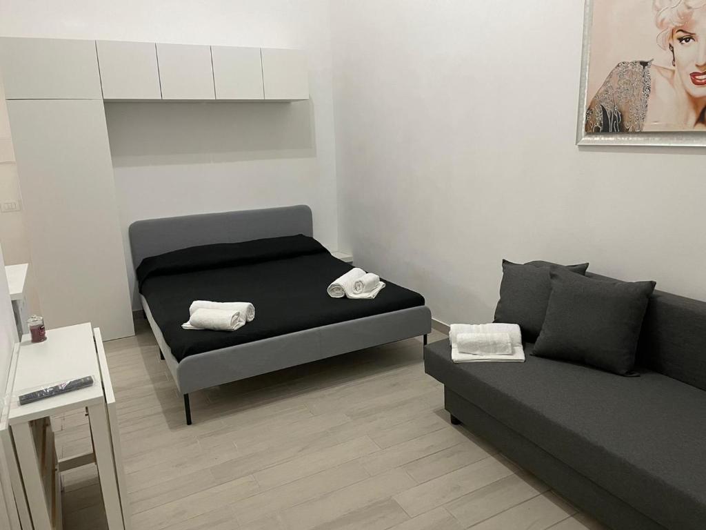 um pequeno quarto com uma cama e um sofá em B&B A FACCI VISTA em Porto Empedocle