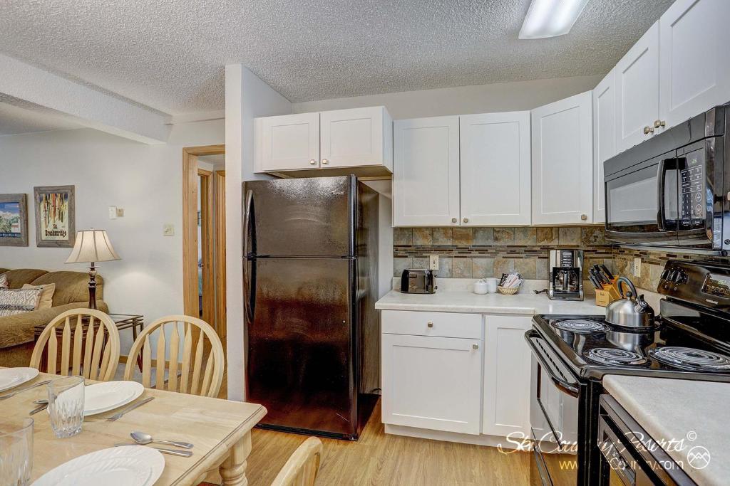 eine Küche mit weißen Schränken und einem schwarzen Kühlschrank in der Unterkunft Charming & Renovated Two-Bedroom Condo Nestled Near a Serene Mountain Stream PM1D in Breckenridge