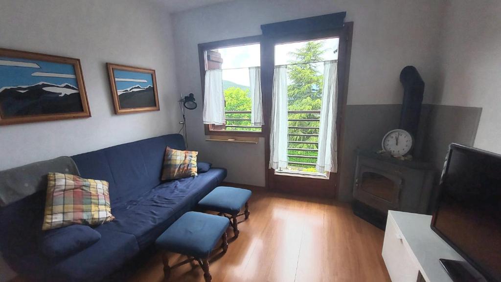 uma sala de estar com um sofá azul e duas janelas em CHECK IN CASAS Pirita em Cerler