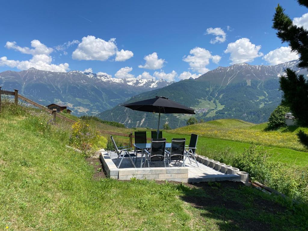 uma mesa e cadeiras com um guarda-sol numa colina em Alpenglück em Fiss