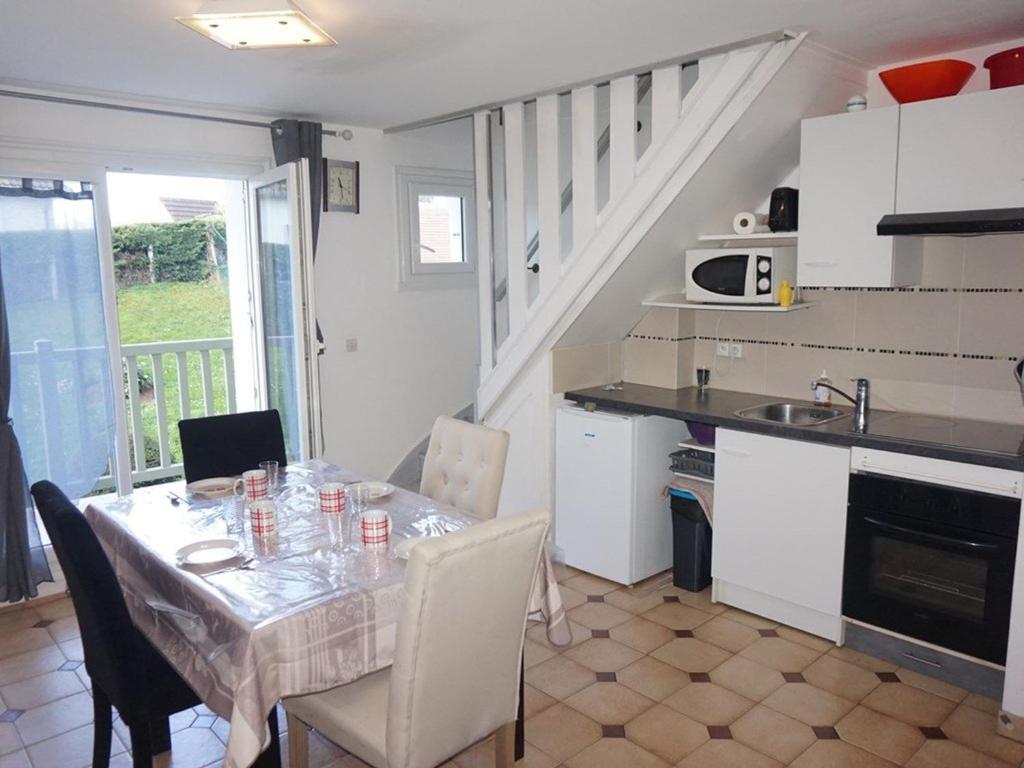 une cuisine avec une table, des chaises et une table, ainsi qu'une cuisine avec un évier dans l'établissement Appartement Merville-Franceville-Plage, 2 pièces, 4 personnes - FR-1-465-11, à Merville-Franceville-Plage