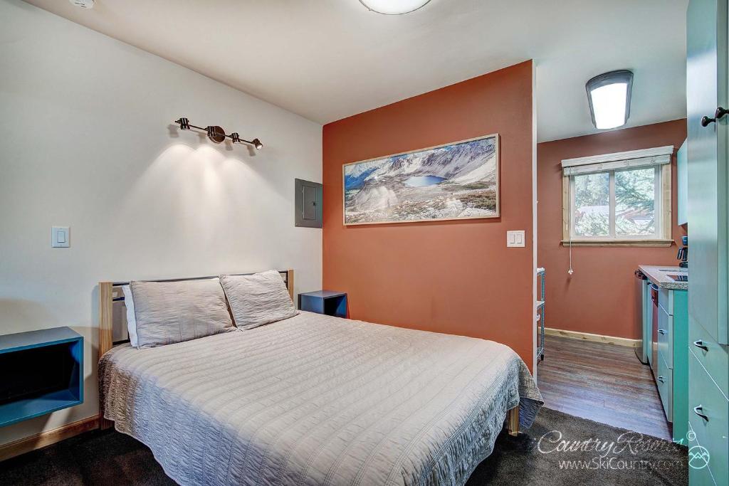 a bedroom with a bed with an orange wall at Completely Renovated Unit, Trendy Top Floor with Many Onsite Amenities PM7D in Breckenridge