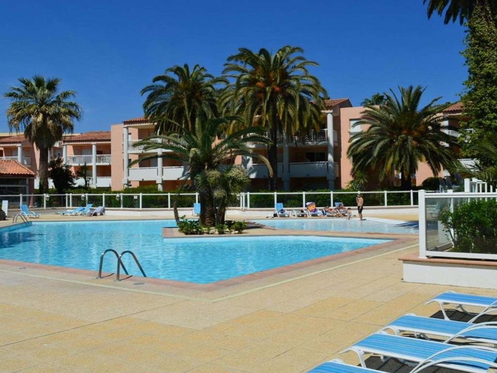 une grande piscine avec des palmiers et des bâtiments dans l'établissement T2 avec piscine et salle de sport, à 400m de la plage, parking inclus - Golfe-Juan - FR-1-252-140, à Vallauris