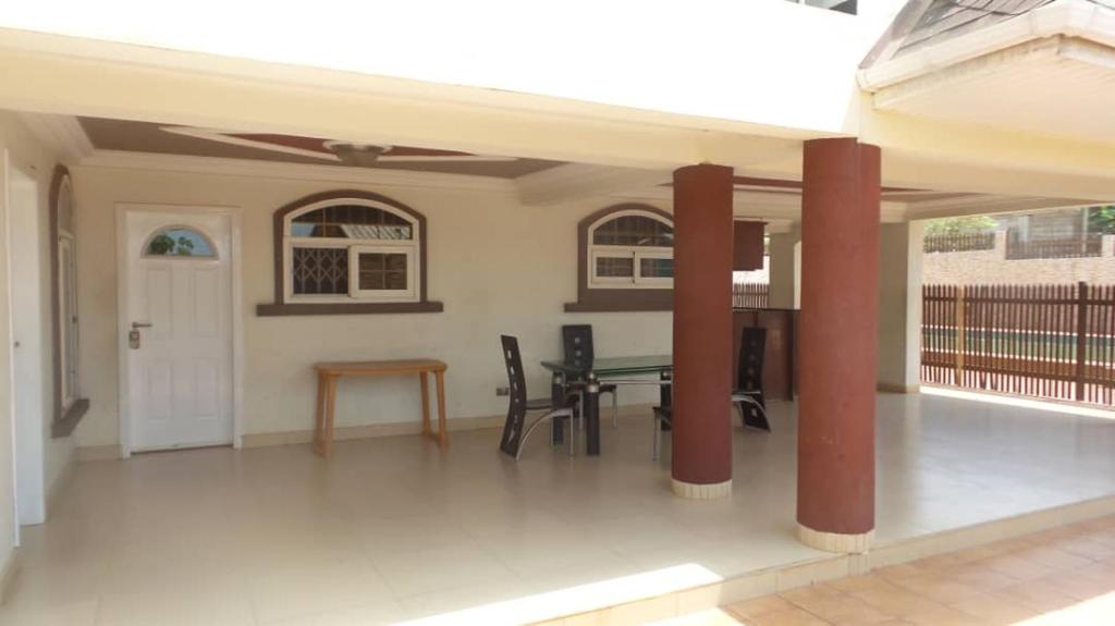 Habitación con patio con mesa y sillas. en Ypool Pacific Homes, en Kumasi