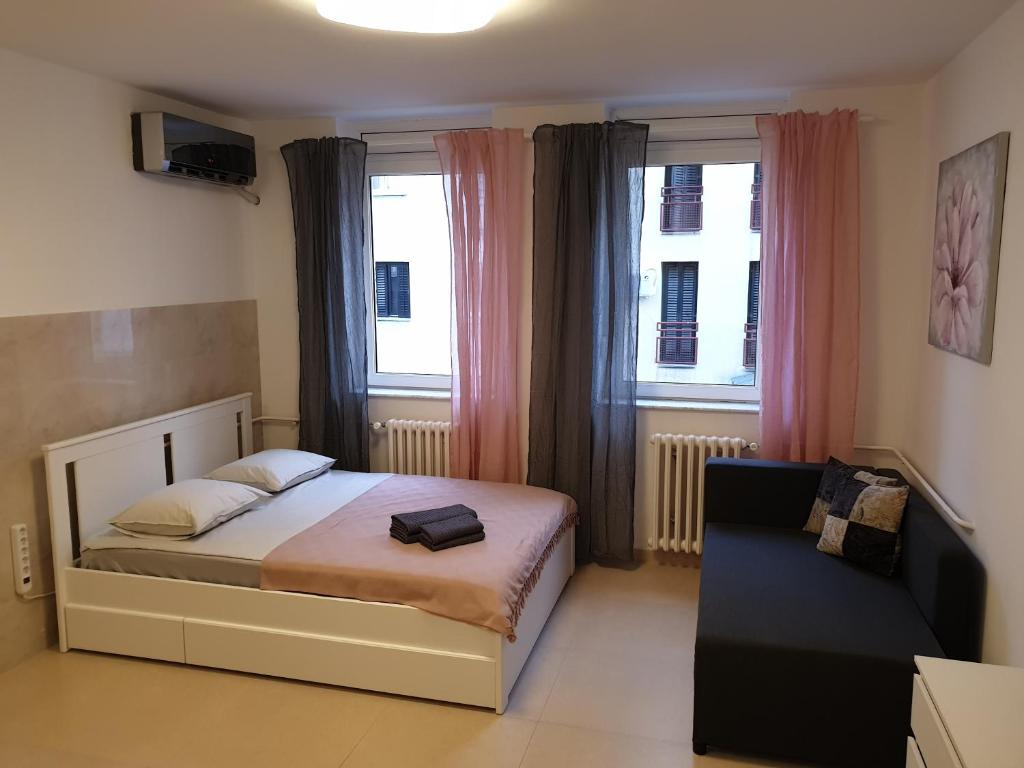 1 dormitorio pequeño con 1 cama y 2 ventanas en Podbara Center, en Novi Sad