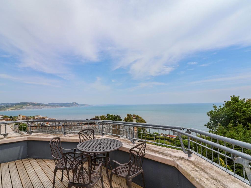 een balkon met een tafel en stoelen en de oceaan bij The Penthouse in Lyme Regis