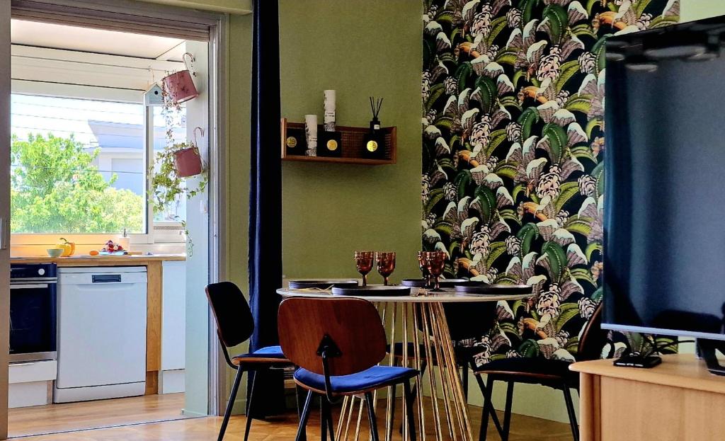 een keuken met een tafel en stoelen met een muur bij L'Étoile Des Sables - Maison de ville climatisée classée 4 étoiles - 4 personnes - Plage de la Grande Conche à 200m - ROYAN in Royan