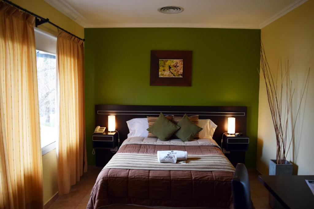 1 dormitorio verde con 1 cama y 2 lámparas en Hotel Suite & Spa Verdesolaro en Villa Elisa