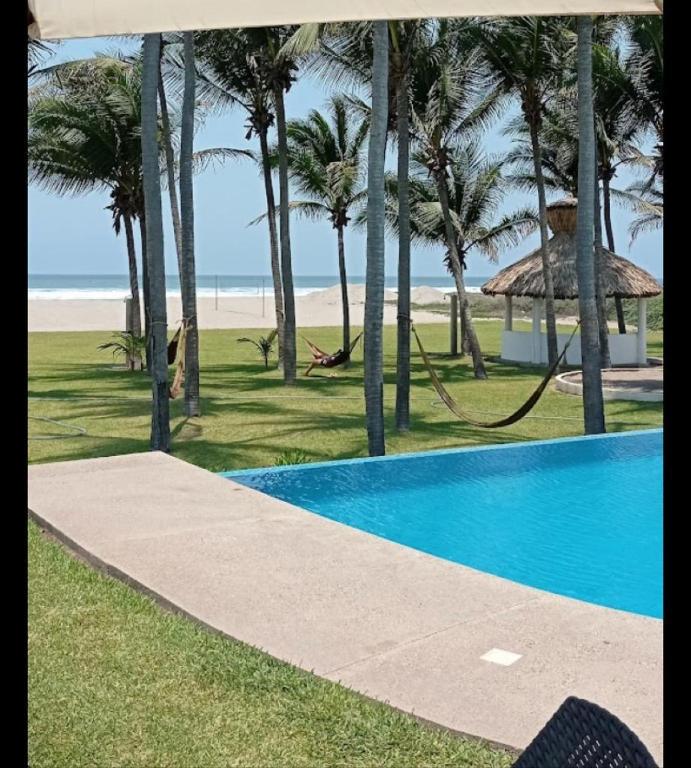 a swimming pool next to a beach with palm trees at Casa Acapulco de mis amores Diamante in Acapulco