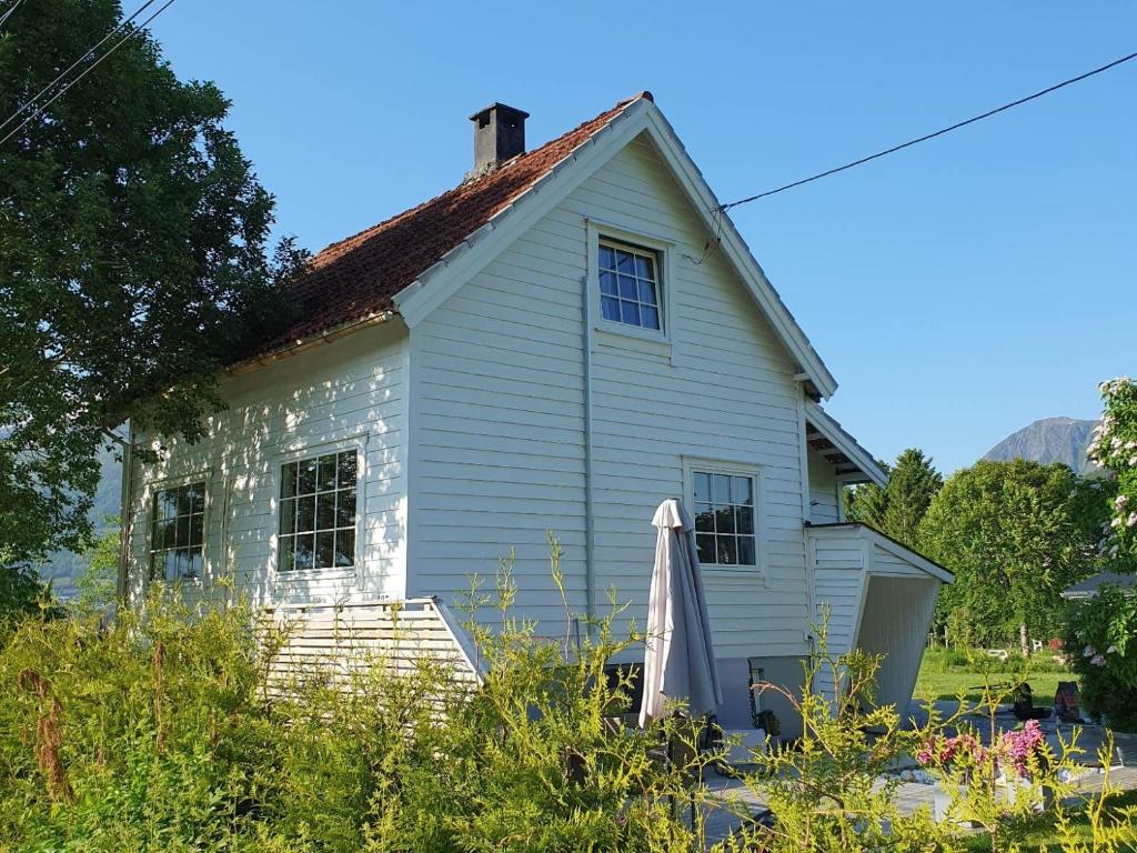 an old white house with a umbrella in front of it at Reinebu in Ørsta