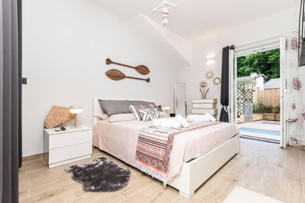 a white bedroom with a bed and a window at Portofino's Little Nest [Wi-Fi & A/C] in Portofino