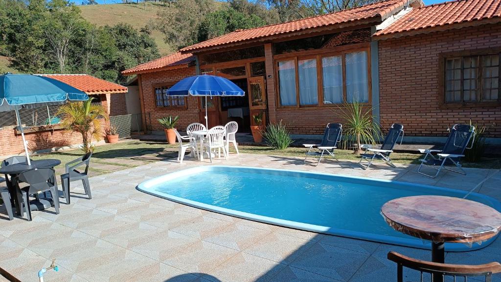 uma piscina com mesa e cadeiras e uma casa em Pousada Estrelícia em Cunha