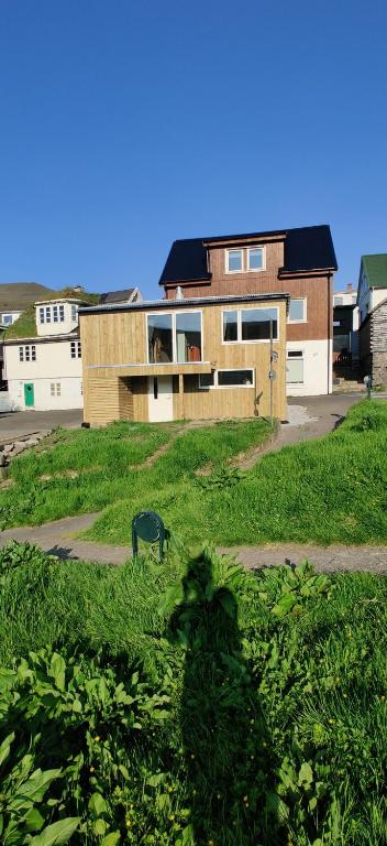 a shadow of a person in the grass in front of a house at The Kontor in Sandavágur