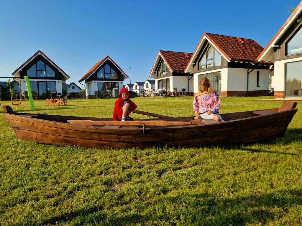 deux enfants assis dans un bateau en bois sur l'herbe dans l'établissement Kaszubia, à Jastrzębia Góra