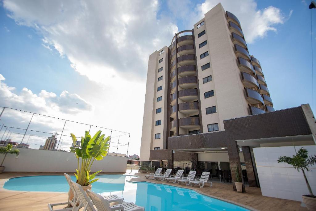 um hotel com piscina em frente a um edifício em ApartDamani em Foz do Iguaçu