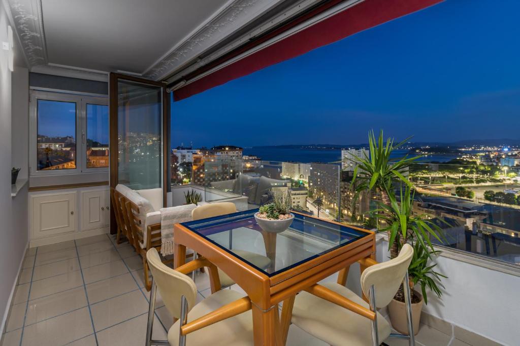 a balcony with a glass table and chairs at El Balcón de Charles in Santander