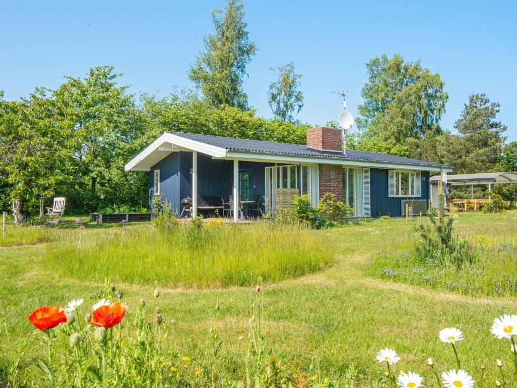 uma casa azul num campo com flores em Holiday home Ørsted XXVI em Ørsted