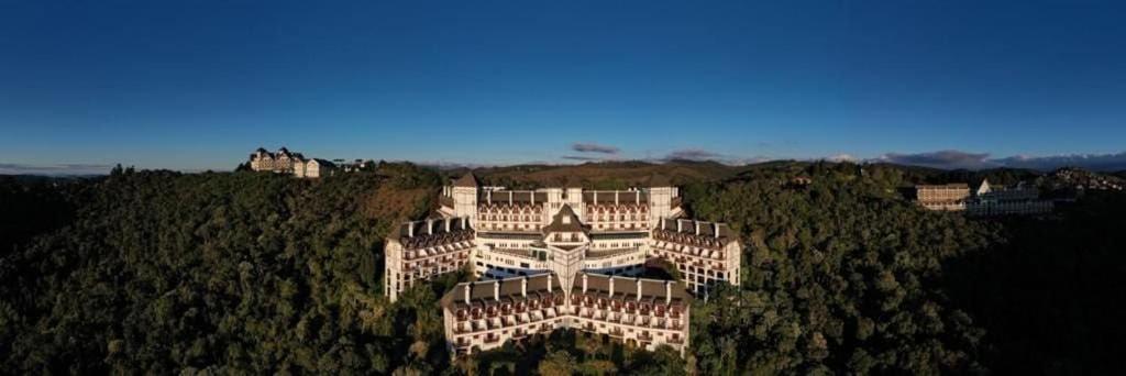 um grande edifício no topo de uma colina com árvores em Flat 5 estrelas em Campos do Jordão em Campos de Jordão
