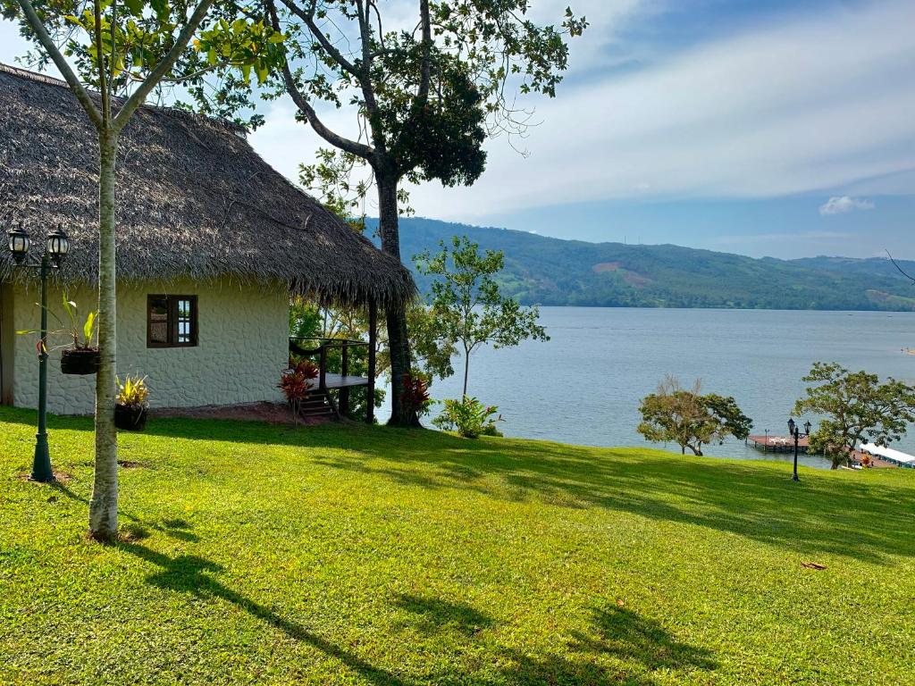 a house with a grass roof and a lake at Sauce Lodge - Laguna Azul in Sauce