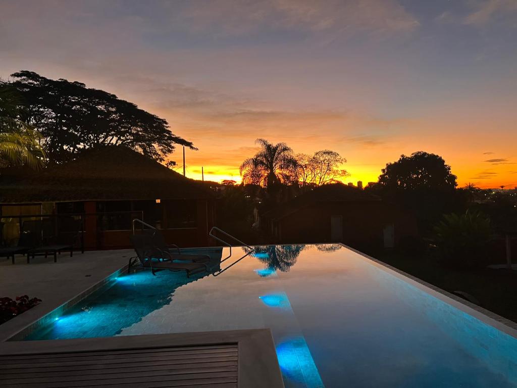 une piscine avec vue sur le coucher du soleil en arrière-plan dans l'établissement Quinta dos Lemos, à Araxá
