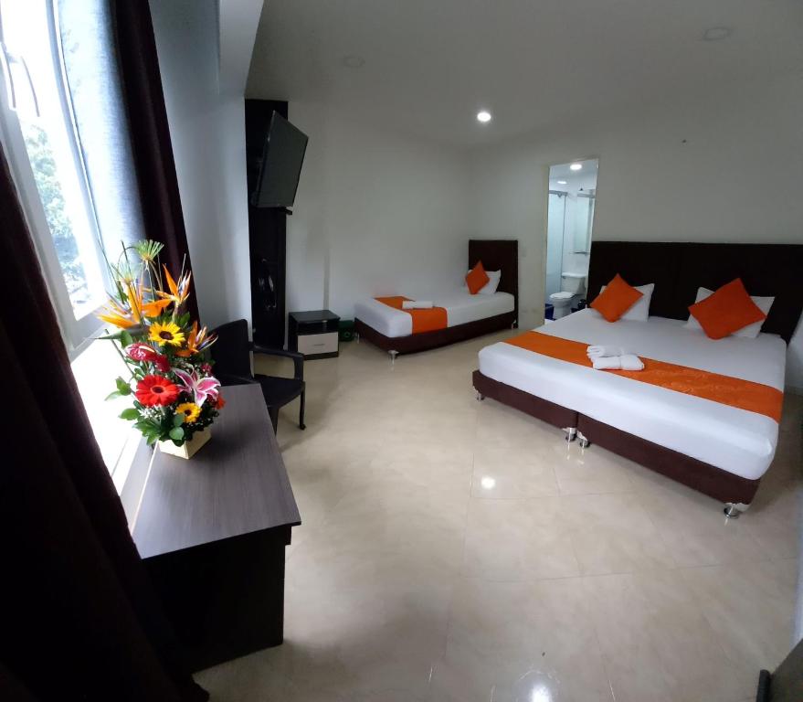 pokój hotelowy z dwoma łóżkami i kwiatami na stole w obiekcie HOTEL RAI MEDELLIN w mieście Medellín