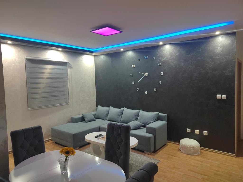 uma sala de estar com um sofá e um relógio na parede em Grand apartman em Belgrado