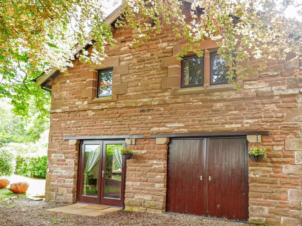 a brick house with a garage in front of it at Cairngarth Cottage in How