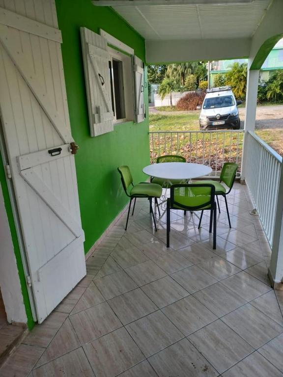 eine Terrasse mit einem Tisch und Stühlen sowie einer grünen Wand in der Unterkunft Mancenillier in Petit-Canal