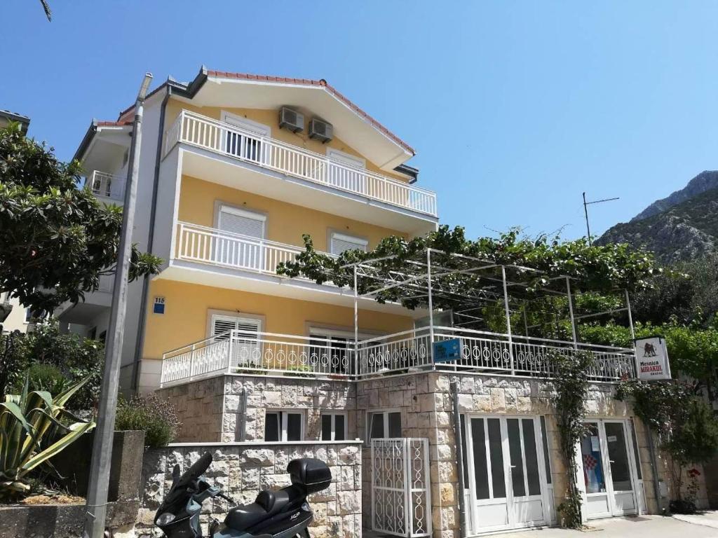 une maison jaune avec une moto garée devant elle dans l'établissement Apartments with a parking space Gradac, Makarska - 21437, à Gradac