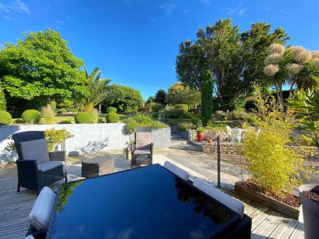 eine Terrasse mit einem Tisch, Stühlen und Bäumen in der Unterkunft Holiday Home, Neville-sur-Mer in Néville-sur-Mer