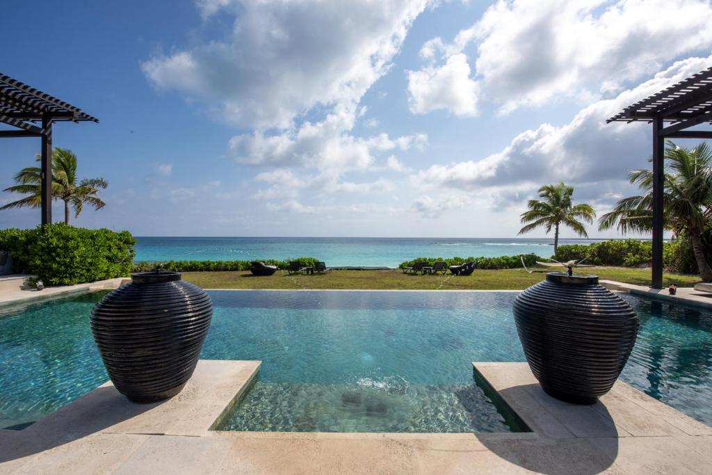 Dos jarrones grandes sentados en una piscina con vistas al océano en Ananda House estate en Governor's Harbour
