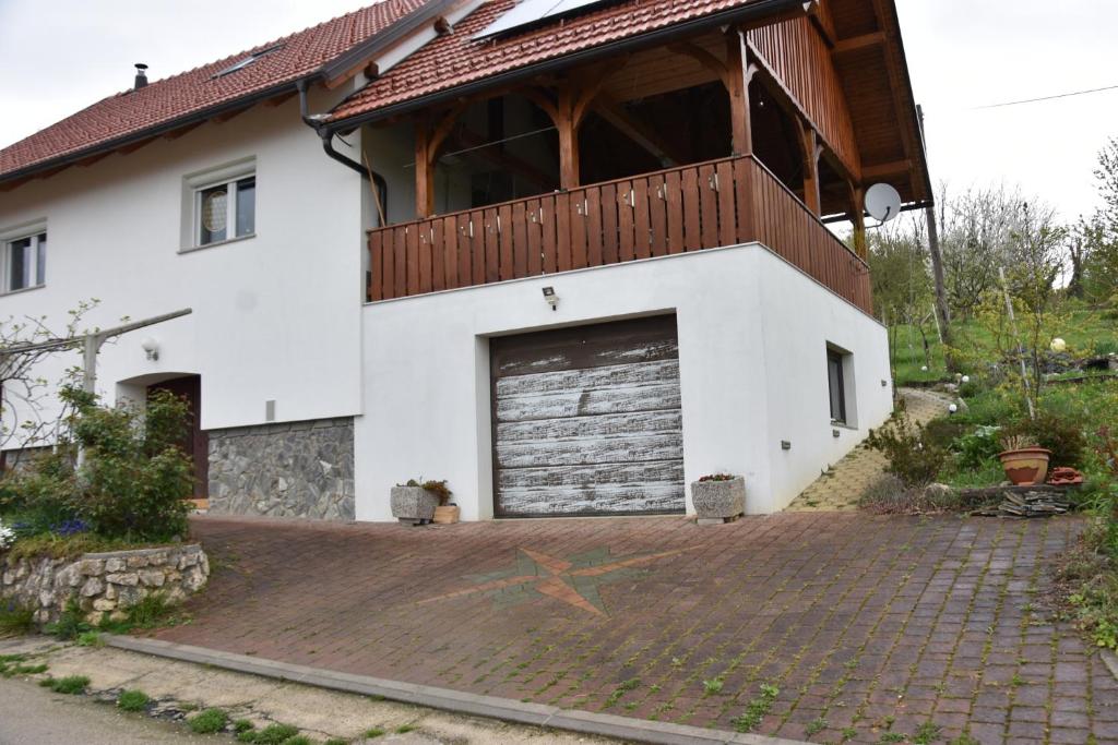 ein weißes Haus mit einer Garage und einem Balkon in der Unterkunft Apartment in Grabrovec - Koroska Unterkärnten 44968 in Metlika