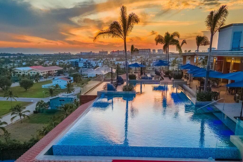 een zwembad van het resort met een zonsondergang op de achtergrond bij Beautiful 3BR Condo with amazing rooftop terrace in Nuevo Vallarta 